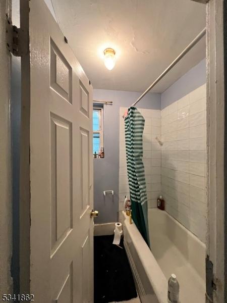 full bath featuring shower / bathtub combination with curtain and baseboards