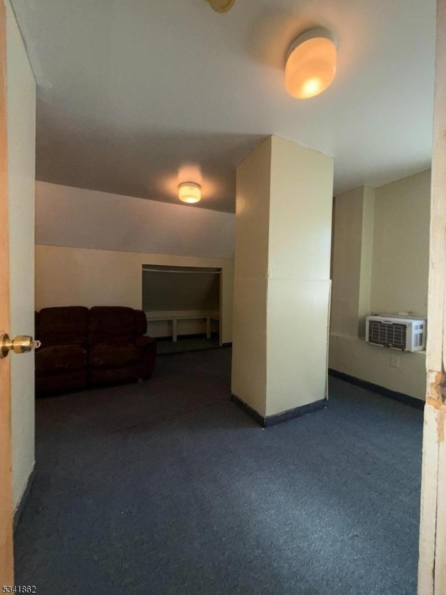 interior space featuring an AC wall unit, carpet flooring, vaulted ceiling, and baseboards