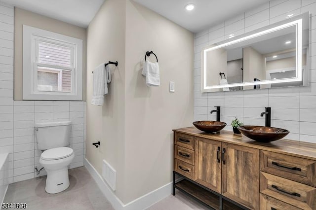 bathroom featuring visible vents, a sink, toilet, and double vanity