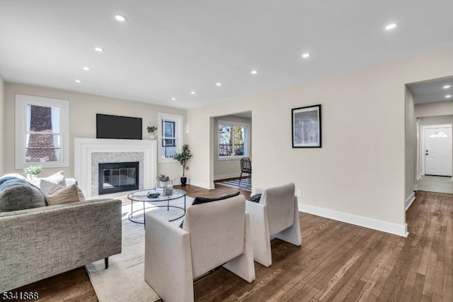 living room with baseboards, a glass covered fireplace, wood finished floors, and recessed lighting