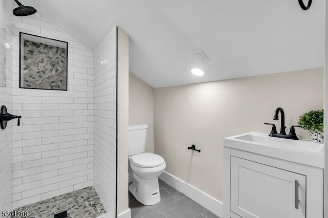 full bathroom featuring baseboards, tiled shower, toilet, lofted ceiling, and tile patterned flooring