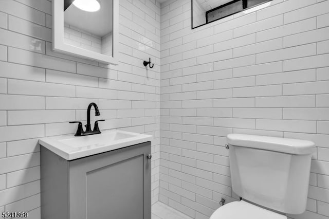 bathroom with tile walls, vanity, and toilet