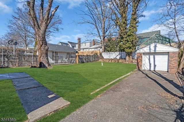 view of yard featuring a detached garage, fence, aphalt driveway, and an outdoor structure