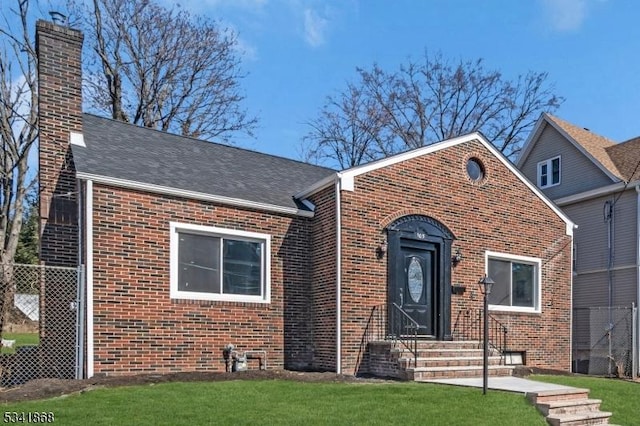 view of front of home featuring brick siding, a chimney, and a front lawn