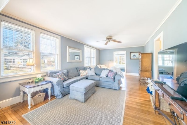 living room with baseboards, crown molding, and light wood finished floors