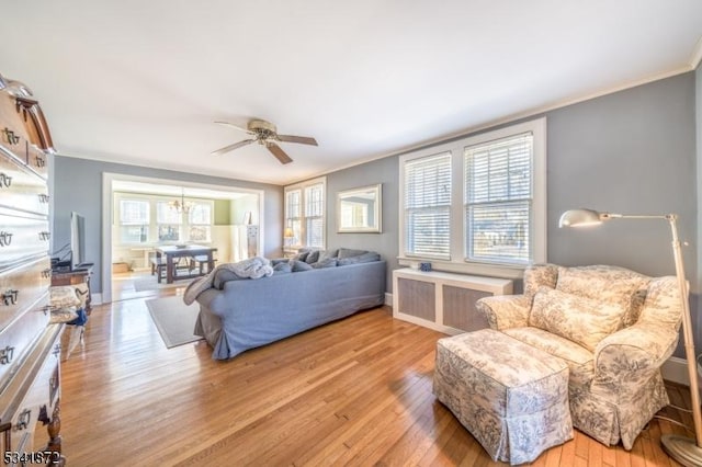 living room featuring baseboards, radiator heating unit, ceiling fan, ornamental molding, and wood finished floors