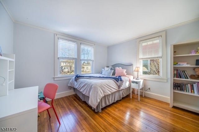 bedroom featuring ornamental molding, hardwood / wood-style flooring, and baseboards