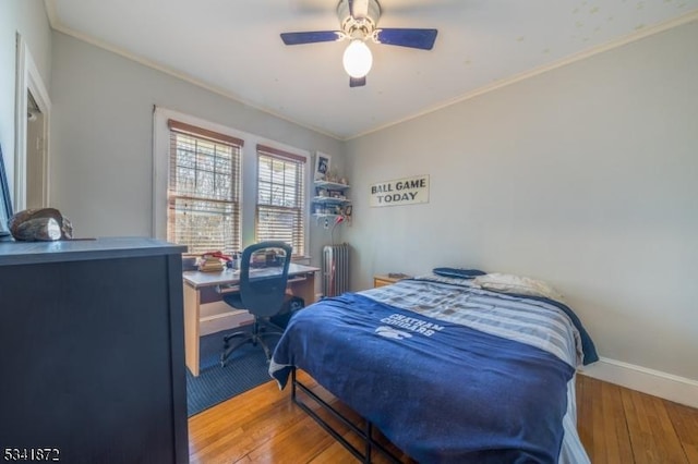 bedroom featuring baseboards, radiator, ceiling fan, hardwood / wood-style floors, and crown molding