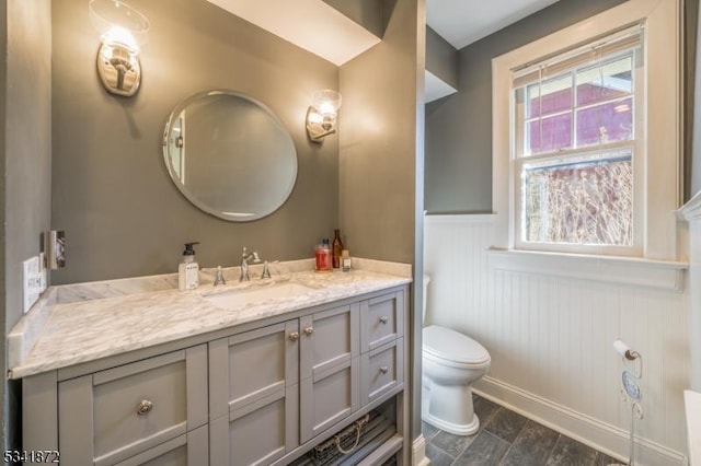 bathroom with wainscoting, vanity, and toilet