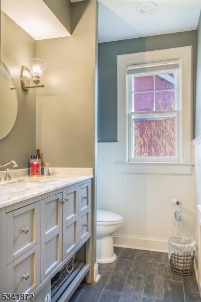 full bath featuring a wainscoted wall, double vanity, and toilet