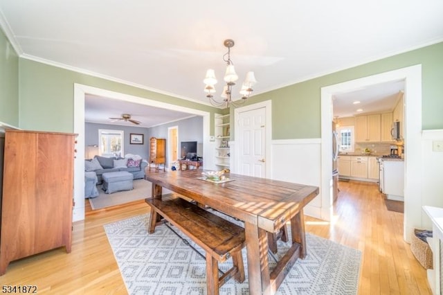 dining space featuring ceiling fan with notable chandelier, ornamental molding, and light wood-type flooring