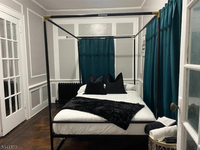 bedroom with radiator heating unit, a decorative wall, and crown molding