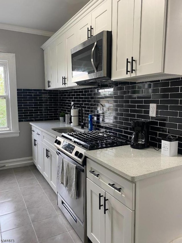 kitchen featuring stainless steel appliances, white cabinetry, crown molding, and light tile patterned floors