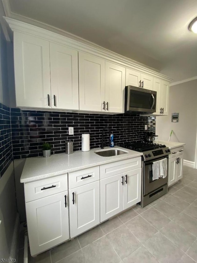 kitchen featuring stainless steel appliances, white cabinetry, a sink, and backsplash