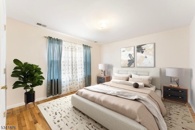 bedroom featuring light wood-style flooring, visible vents, and baseboards