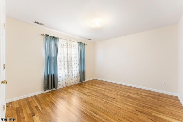 spare room featuring baseboards, visible vents, and light wood-style floors