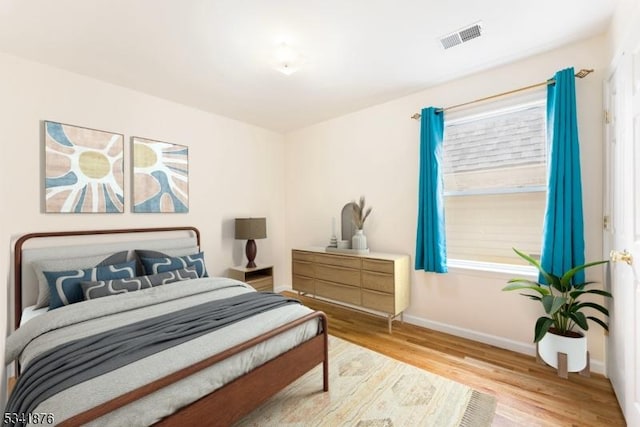 bedroom featuring wood finished floors, visible vents, and baseboards