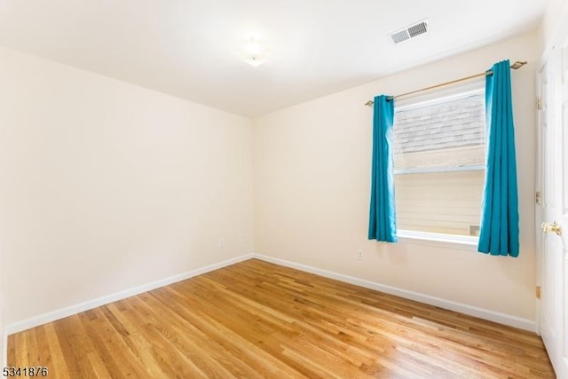 spare room featuring visible vents, baseboards, and wood finished floors