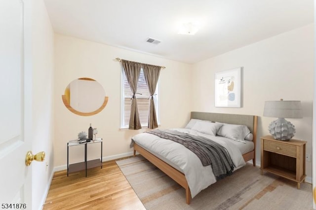 bedroom featuring wood finished floors, visible vents, and baseboards