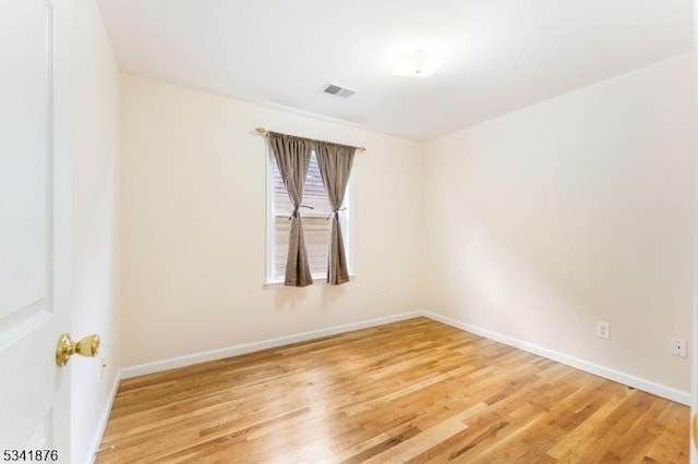 spare room featuring visible vents, baseboards, and wood finished floors