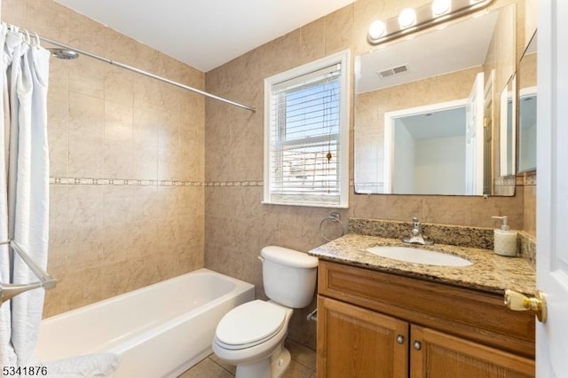 full bathroom featuring visible vents, toilet, shower / tub combo with curtain, vanity, and tile walls