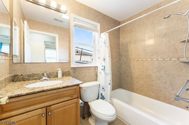 full bath with shower / bath combo, visible vents, toilet, vanity, and tile walls