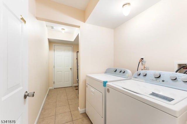 laundry area with light tile patterned floors, baseboards, and washer and clothes dryer