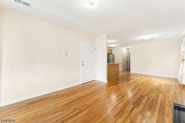 spare room with light wood-type flooring, baseboards, and visible vents