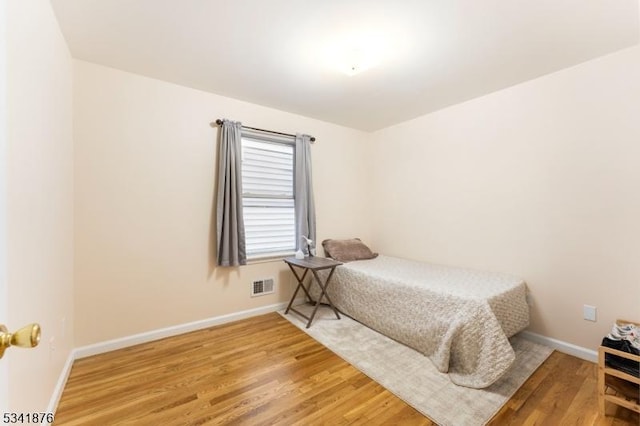 bedroom featuring light wood-style floors, visible vents, and baseboards