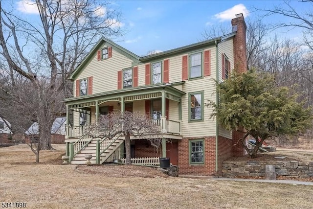 view of front of property featuring covered porch, brick siding, a chimney, and stairs