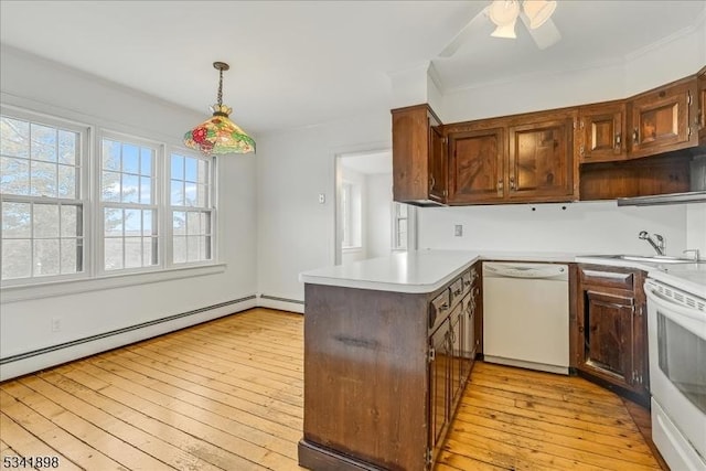 kitchen featuring a peninsula, white appliances, a sink, light countertops, and light wood-type flooring