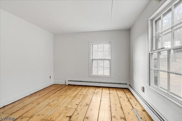 spare room featuring a baseboard radiator, baseboards, and light wood-style flooring