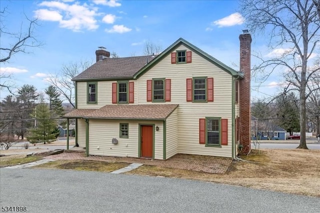 traditional home with roof with shingles and a chimney