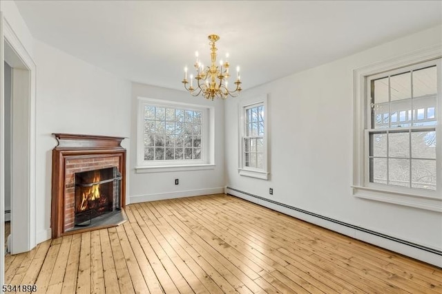 unfurnished living room featuring a fireplace, baseboard heating, an inviting chandelier, baseboards, and hardwood / wood-style flooring