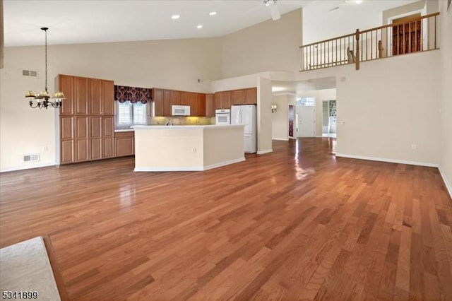 kitchen featuring white appliances, visible vents, open floor plan, and light wood finished floors