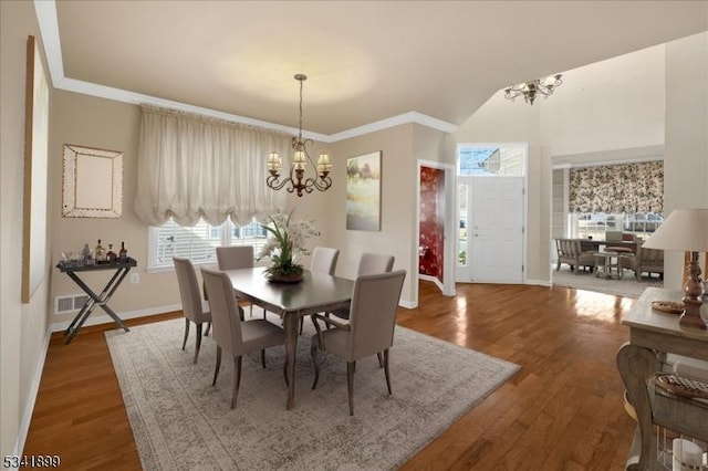 dining space with an inviting chandelier, wood finished floors, and ornamental molding