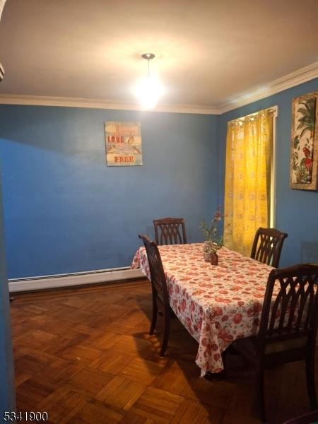 dining area featuring a baseboard heating unit and crown molding