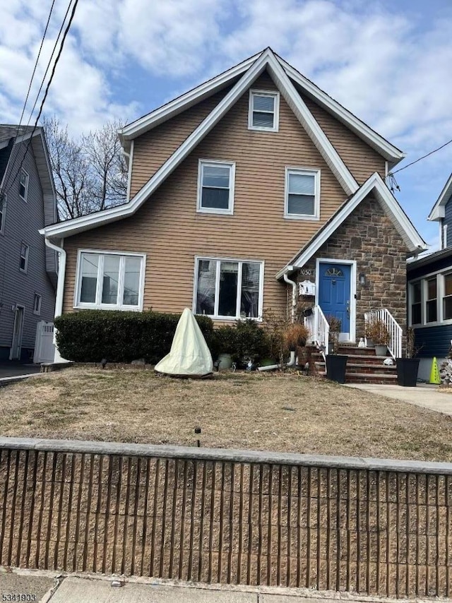 view of front of house with stone siding, a fenced front yard, and cooling unit