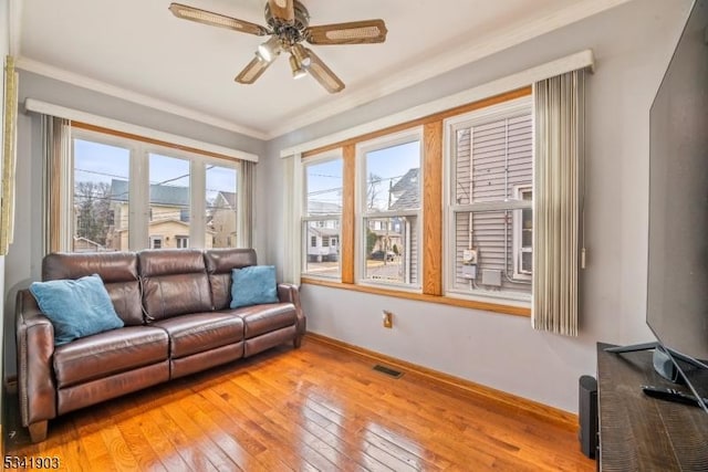 living room featuring ornamental molding, visible vents, plenty of natural light, and light wood finished floors