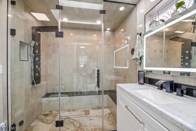 full bath with tile walls, marble finish floor, vanity, and a shower stall