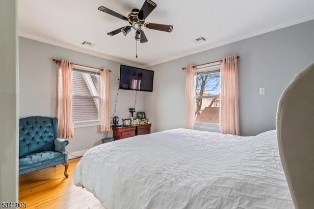 bedroom featuring baseboards, visible vents, wood finished floors, and ornamental molding