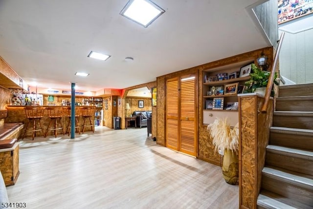 below grade area featuring stairway, a bar, and wood finished floors