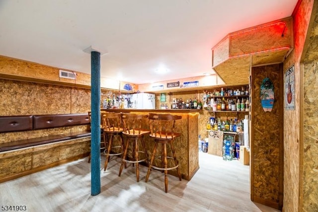 bar featuring a bar, visible vents, and wood finished floors