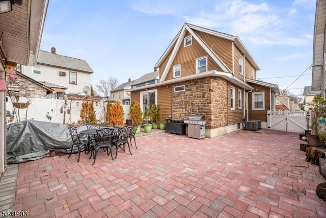 view of patio with outdoor dining area, fence, a gate, and central air condition unit