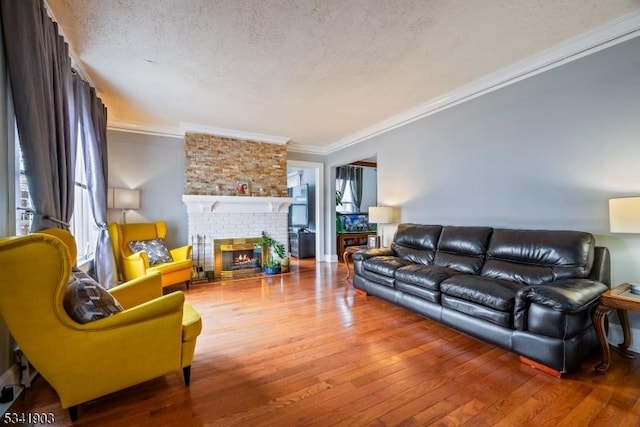 living area featuring a textured ceiling, ornamental molding, a fireplace, and hardwood / wood-style floors