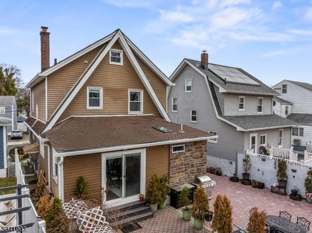 back of property with a chimney, a shingled roof, entry steps, a patio area, and fence