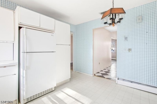 kitchen with visible vents, freestanding refrigerator, tile walls, white cabinets, and light floors