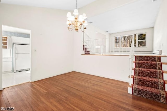 unfurnished living room with a notable chandelier and wood finished floors