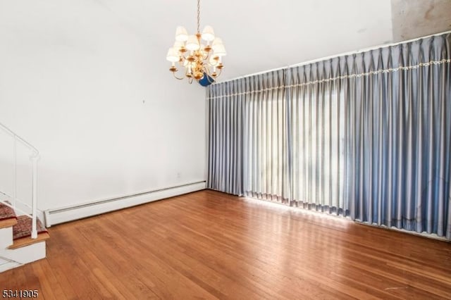 empty room featuring a baseboard heating unit, stairway, wood finished floors, and a chandelier