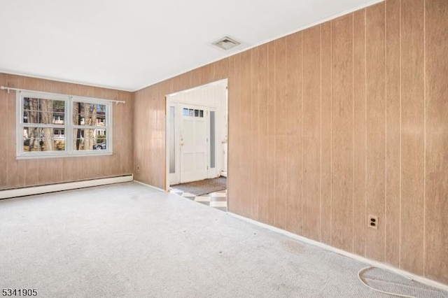 empty room featuring a baseboard heating unit, wooden walls, carpet, and visible vents